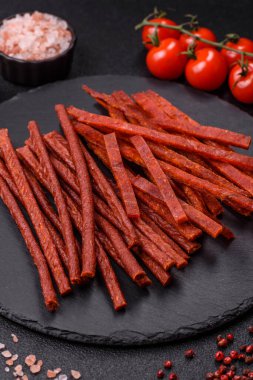 Koyu beton zeminde tuzlu ve baharatlı kurutulmuş balık çubukları.