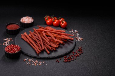 Koyu beton zeminde tuzlu ve baharatlı kurutulmuş balık çubukları.