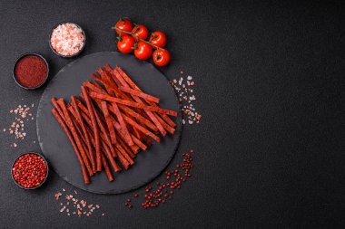 Koyu beton zeminde tuzlu ve baharatlı kurutulmuş balık çubukları.