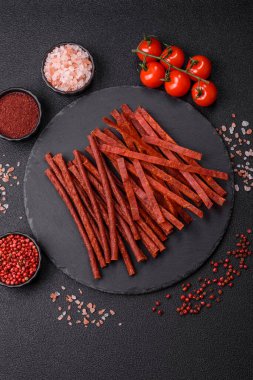 Koyu beton zeminde tuzlu ve baharatlı kurutulmuş balık çubukları.