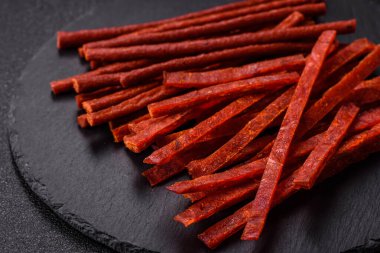 Koyu beton zeminde tuzlu ve baharatlı kurutulmuş balık çubukları.