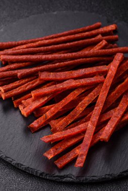 Koyu beton zeminde tuzlu ve baharatlı kurutulmuş balık çubukları.