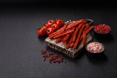 Koyu beton zeminde tuzlu ve baharatlı kurutulmuş balık çubukları.