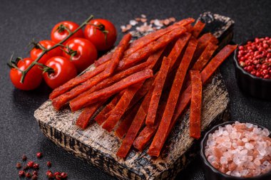 Koyu beton zeminde tuzlu ve baharatlı kurutulmuş balık çubukları.