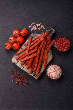 Koyu beton zeminde tuzlu ve baharatlı kurutulmuş balık çubukları.