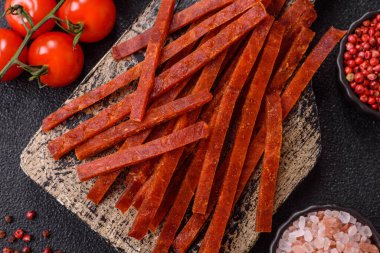 Koyu beton zeminde tuzlu ve baharatlı kurutulmuş balık çubukları.