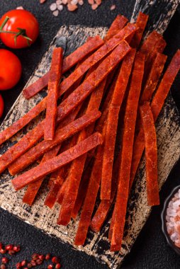 Koyu beton zeminde tuzlu ve baharatlı kurutulmuş balık çubukları.