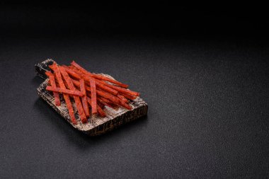 Jerky dried fish sticks with salt and spices on a dark concrete background clipart