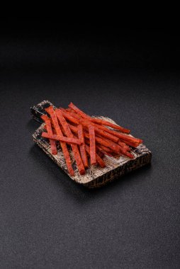 Koyu beton zeminde tuzlu ve baharatlı kurutulmuş balık çubukları.