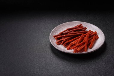 Koyu beton zeminde tuzlu ve baharatlı kurutulmuş balık çubukları.