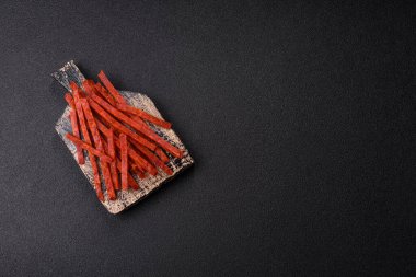 Koyu beton zeminde tuzlu ve baharatlı kurutulmuş balık çubukları.