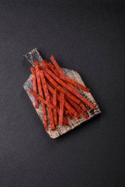 Koyu beton zeminde tuzlu ve baharatlı kurutulmuş balık çubukları.