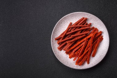 Koyu beton zeminde tuzlu ve baharatlı kurutulmuş balık çubukları.