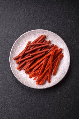 Koyu beton zeminde tuzlu ve baharatlı kurutulmuş balık çubukları.