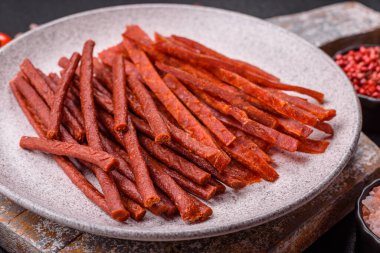 Koyu beton zeminde tuzlu ve baharatlı kurutulmuş balık çubukları.