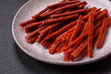 Koyu beton zeminde tuzlu ve baharatlı kurutulmuş balık çubukları.