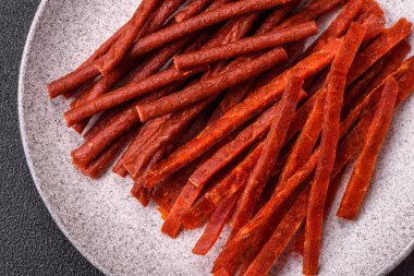 Koyu beton zeminde tuzlu ve baharatlı kurutulmuş balık çubukları.