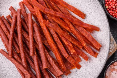 Koyu beton zeminde tuzlu ve baharatlı kurutulmuş balık çubukları.