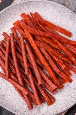 Koyu beton zeminde tuzlu ve baharatlı kurutulmuş balık çubukları.