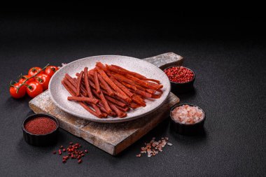 Koyu beton zeminde tuzlu ve baharatlı kurutulmuş balık çubukları.