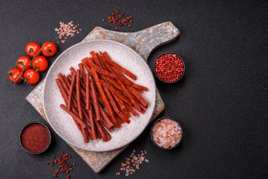 Koyu beton zeminde tuzlu ve baharatlı kurutulmuş balık çubukları.