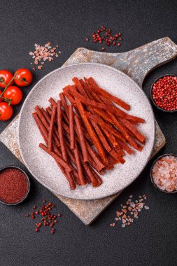 Koyu beton zeminde tuzlu ve baharatlı kurutulmuş balık çubukları.