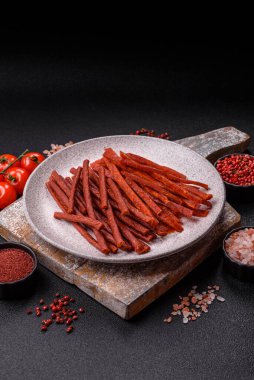 Jerky dried fish sticks with salt and spices on a dark concrete background clipart