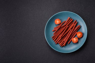 Koyu beton zeminde tuzlu ve baharatlı kurutulmuş balık çubukları.