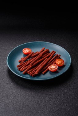 Koyu beton zeminde tuzlu ve baharatlı kurutulmuş balık çubukları.