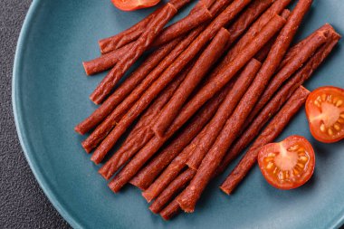 Koyu beton zeminde tuzlu ve baharatlı kurutulmuş balık çubukları.