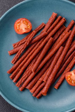 Koyu beton zeminde tuzlu ve baharatlı kurutulmuş balık çubukları.