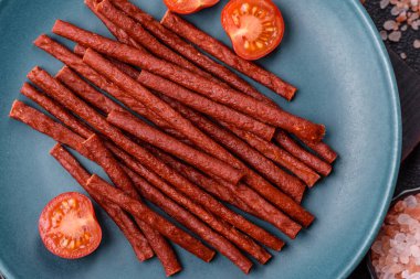 Koyu beton zeminde tuzlu ve baharatlı kurutulmuş balık çubukları.