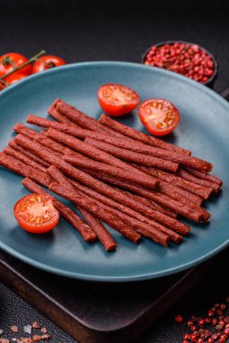 Koyu beton zeminde tuzlu ve baharatlı kurutulmuş balık çubukları.