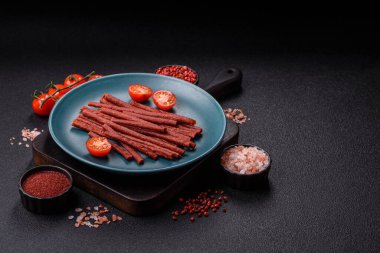 Koyu beton zeminde tuzlu ve baharatlı kurutulmuş balık çubukları.