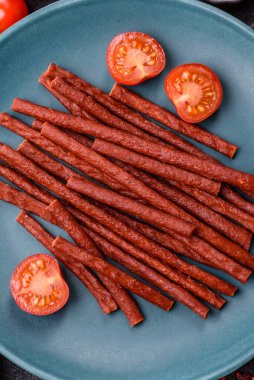 Koyu beton zeminde tuzlu ve baharatlı kurutulmuş balık çubukları.