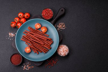 Koyu beton zeminde tuzlu ve baharatlı kurutulmuş balık çubukları.