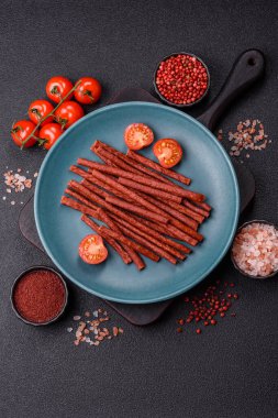 Koyu beton zeminde tuzlu ve baharatlı kurutulmuş balık çubukları.