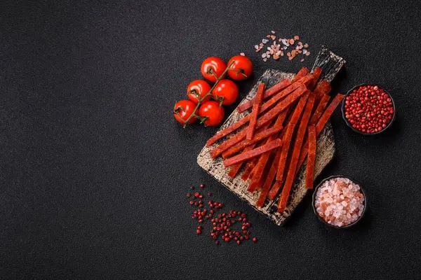 Koyu beton zeminde tuzlu ve baharatlı kurutulmuş balık çubukları.