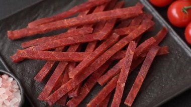 Koyu beton zeminde tuzlu ve baharatlı kurutulmuş balık çubukları.