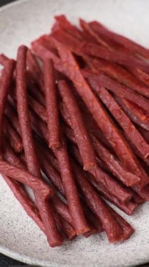 Koyu beton zeminde tuzlu ve baharatlı kurutulmuş balık çubukları.