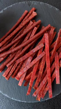 Koyu beton zeminde tuzlu ve baharatlı kurutulmuş balık çubukları.