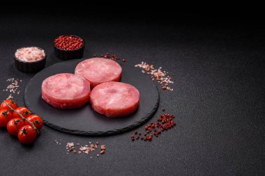 Two fresh slices of raw tuna fillet with spices and herbs on a dark concrete background