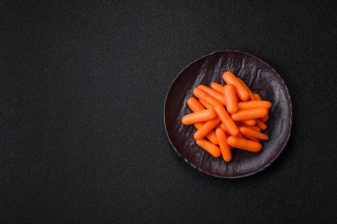 Çiğ minik havuçlar, koyu beton bir zeminde vejetaryen yemeği hazırlamak için malzemedir.