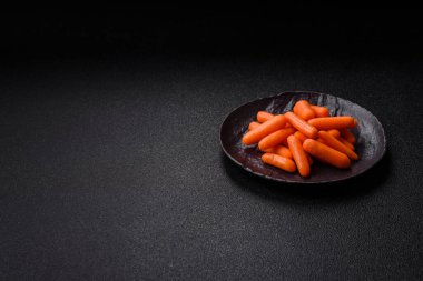 Çiğ minik havuçlar, koyu beton bir zeminde vejetaryen yemeği hazırlamak için malzemedir.