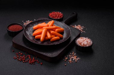 Çiğ minik havuçlar, koyu beton bir zeminde vejetaryen yemeği hazırlamak için malzemedir.