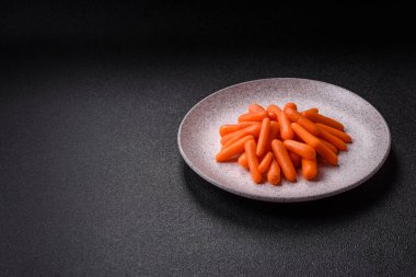 Çiğ minik havuçlar, koyu beton bir zeminde vejetaryen yemeği hazırlamak için malzemedir.