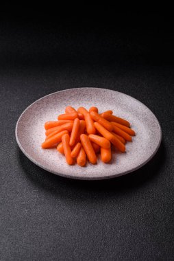 Çiğ minik havuçlar, koyu beton bir zeminde vejetaryen yemeği hazırlamak için malzemedir.