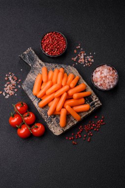 Çiğ minik havuçlar, koyu beton bir zeminde vejetaryen yemeği hazırlamak için malzemedir.