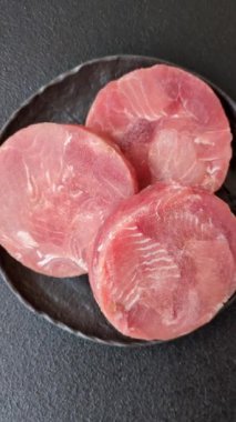 Two fresh slices of raw tuna fillet with spices and herbs on a dark concrete background