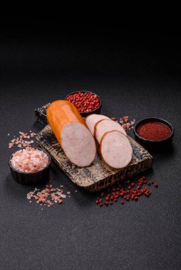 Lezzetli haşlanmış tavuk ya da koyu beton arka planda dilimlenmiş domuz sosisi.